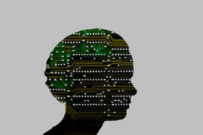 Silhouette of a human head filled with electronic circuit board patterns, symbolizing artificial intelligence and human-machine integration.